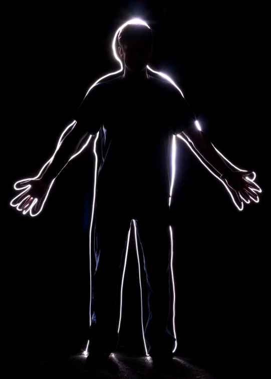 the person is glowing in the dark with his arms outstretched