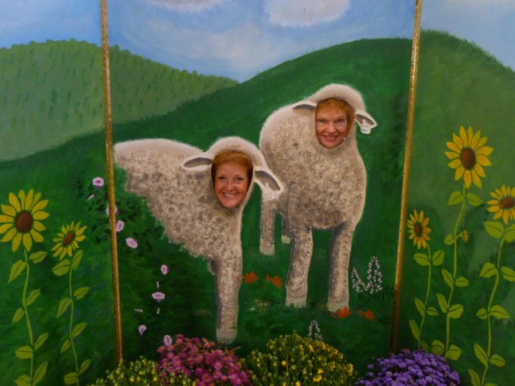 two women stand beside a painting of sheep on display