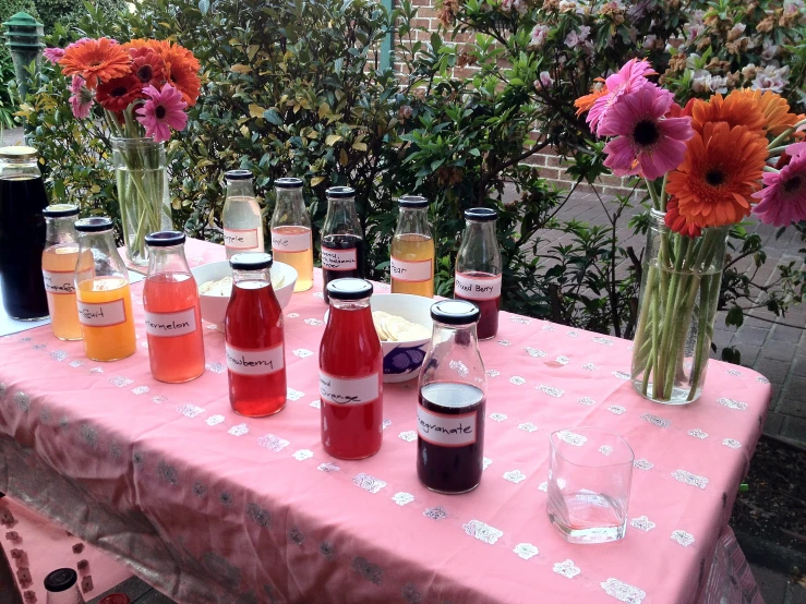 some different types of drinks and flowers in vases