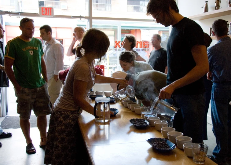 a woman and man that is pouring some liquid into a cup