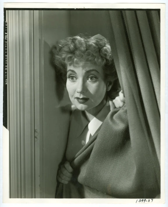 a black and white po of a woman behind curtains