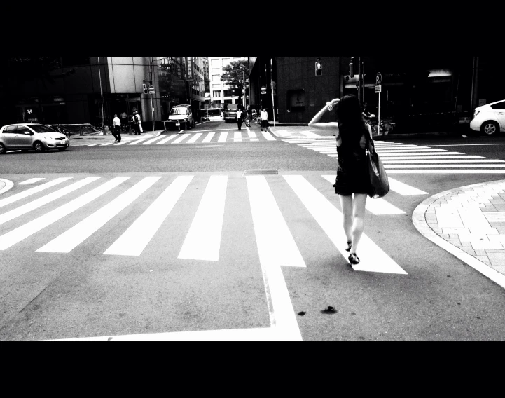 a black and white po of a woman walking across the street