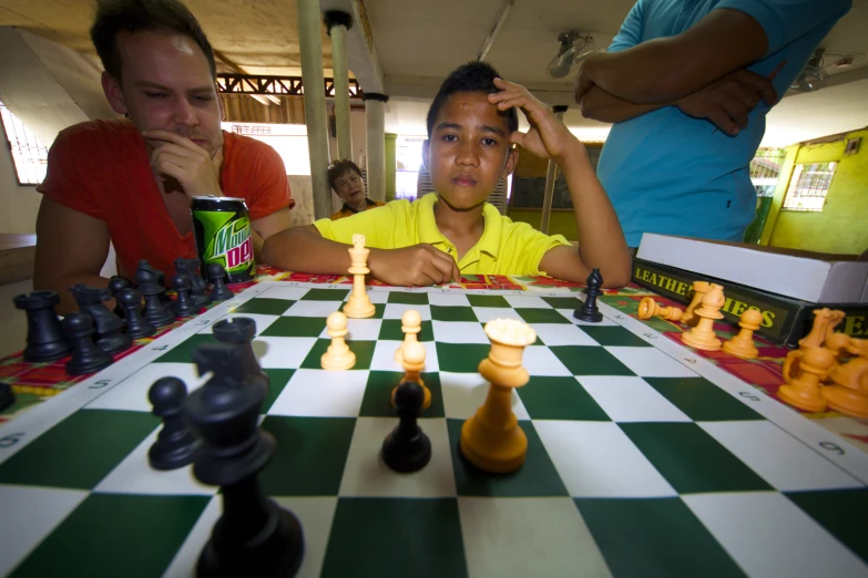 a child is playing chess with other adults