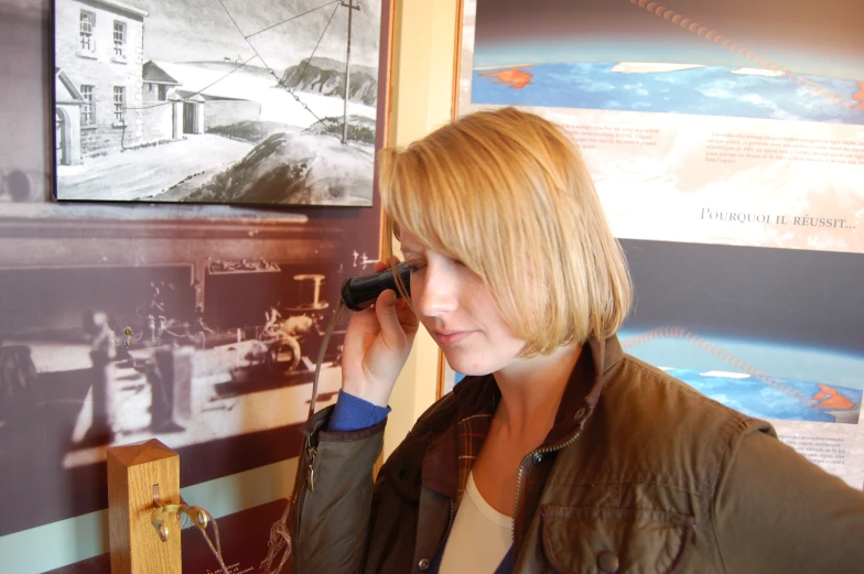 a woman holding her finger up to the nose while looking at a picture