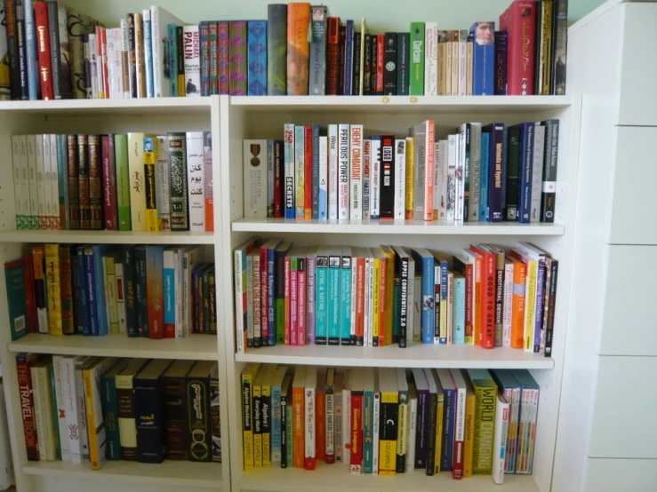 a white book shelf filled with books on top of each other