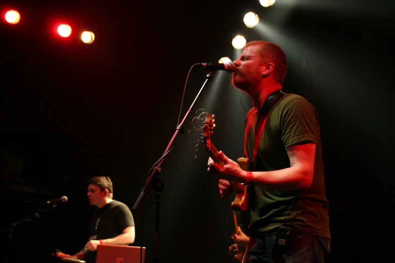 a man with a guitar sings into a microphone