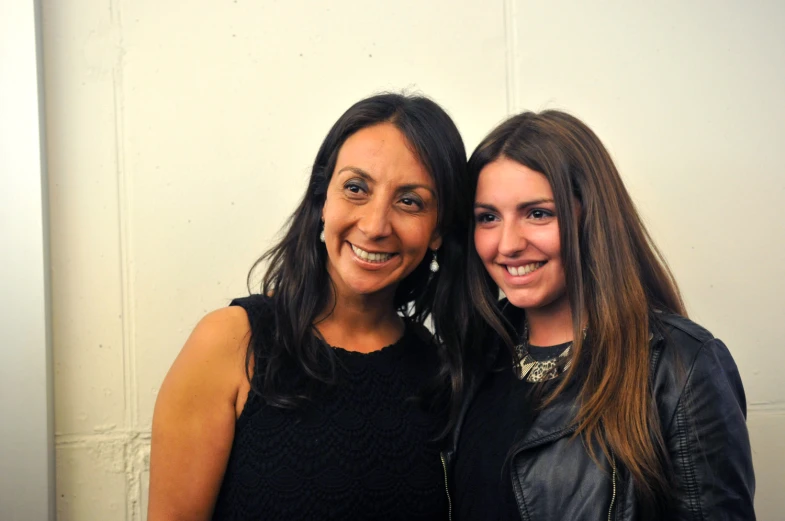 two woman are standing together smiling at the camera