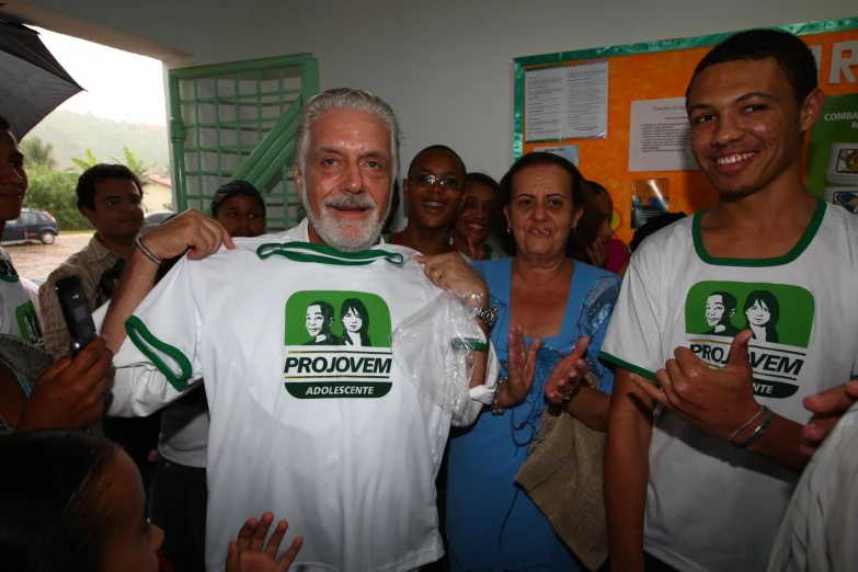 a group of people pose with a man holding a t - shirt