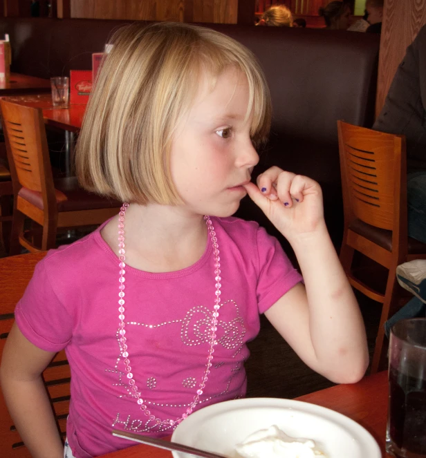 a girl sitting at a table eating food