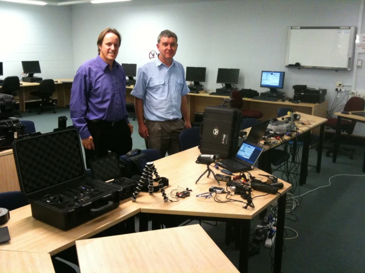 two men looking at some laptops on a table