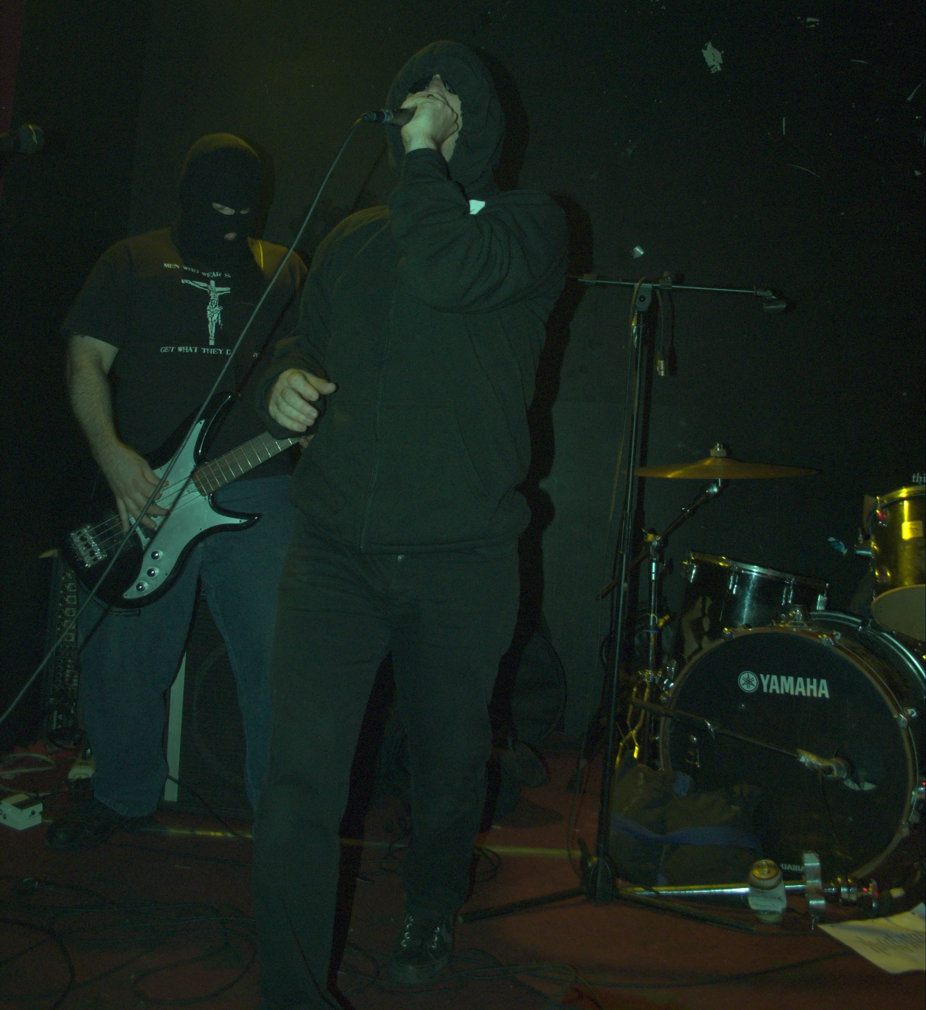 three people on a stage one is playing guitar and the other is singing