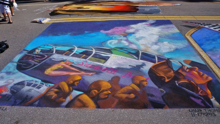 someone painting a mural on the ground with colored chalk