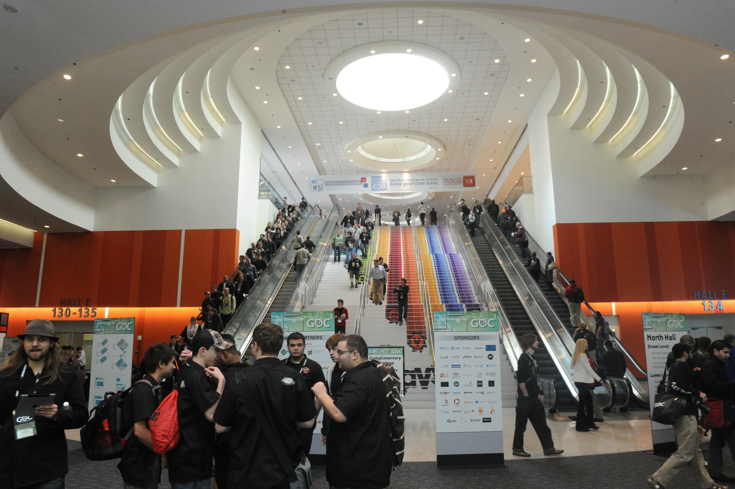 people stand in an open public area next to their escalators