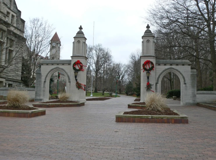 the stone arches in this park are decorated with red and white wreaths