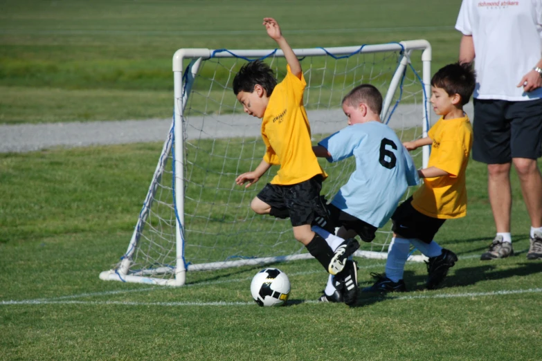 three children wearing blue uniforms are playing soccer