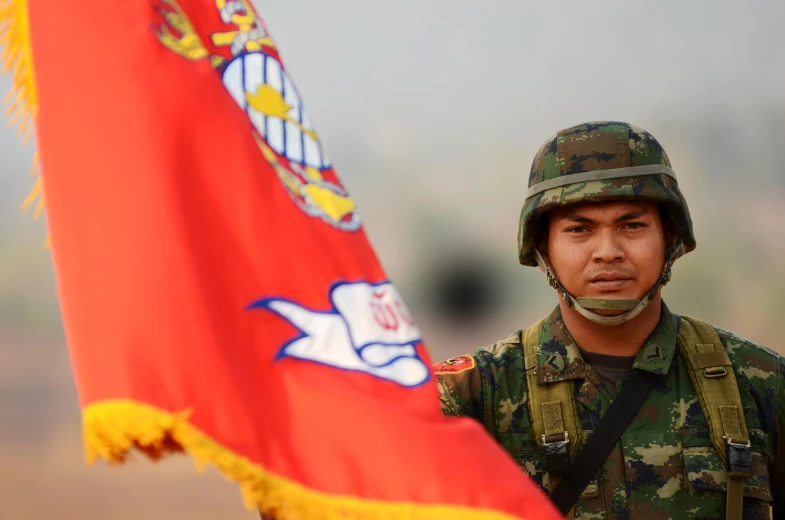 soldier with helmet holding large flag while standing outdoors