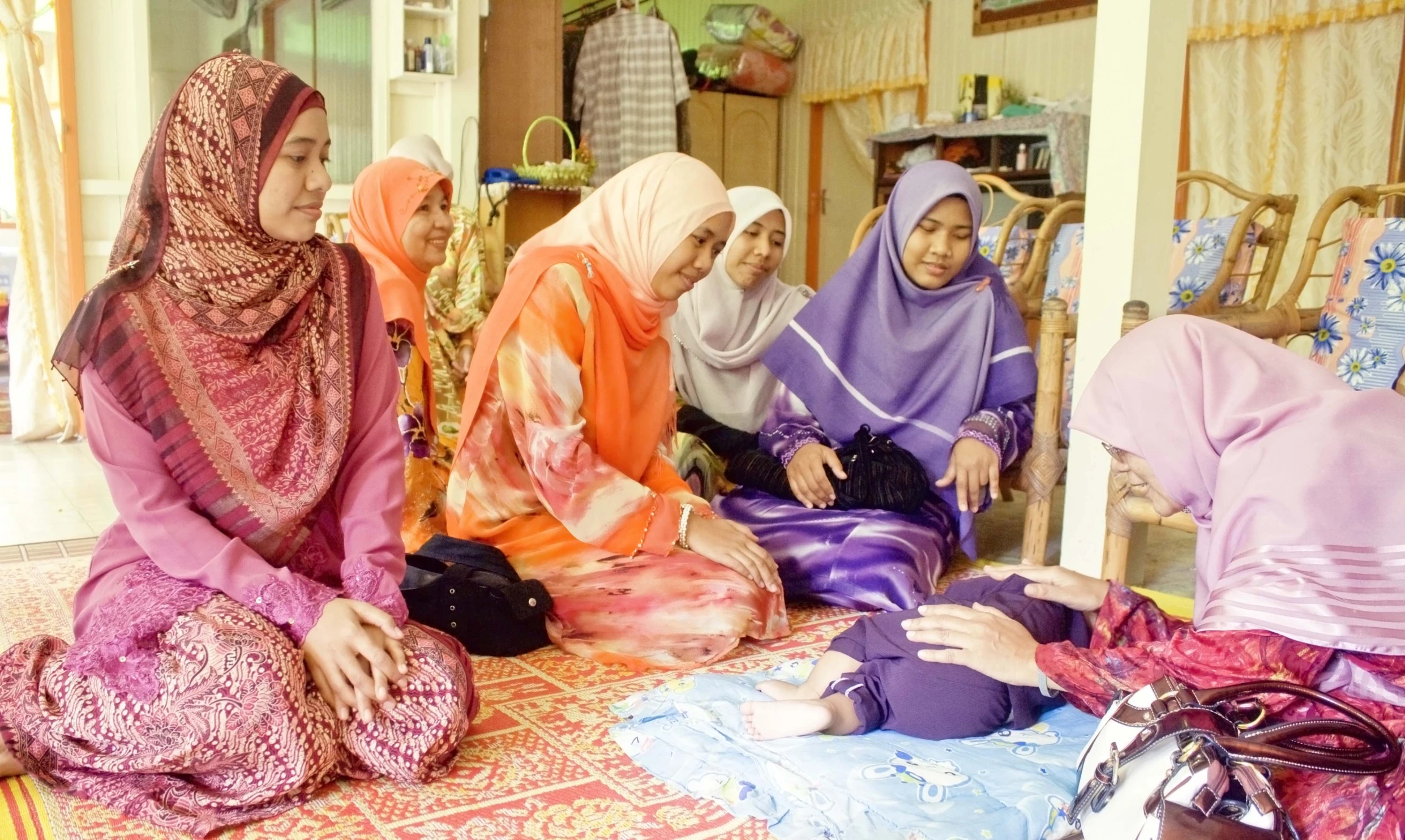 some women wearing different outfits sitting on a floor