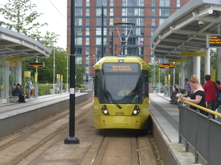 a yellow bus is in the station and people are waiting