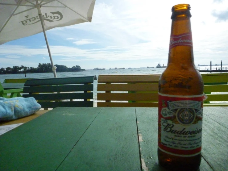 a bottle of beer on a table next to a beach