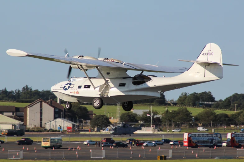 a white airplane landing on a runway with other vehicles