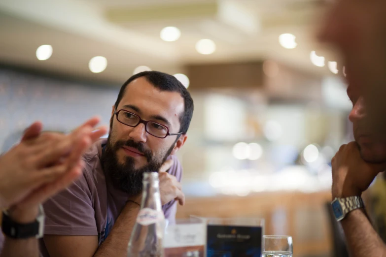 three men are talking with each other at a table