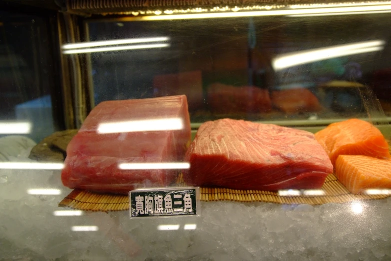 steaks, fish and vegetables on display behind glass