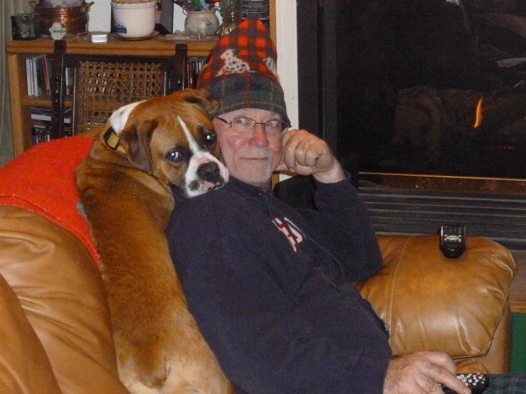 an old man sitting on a brown couch with a dog