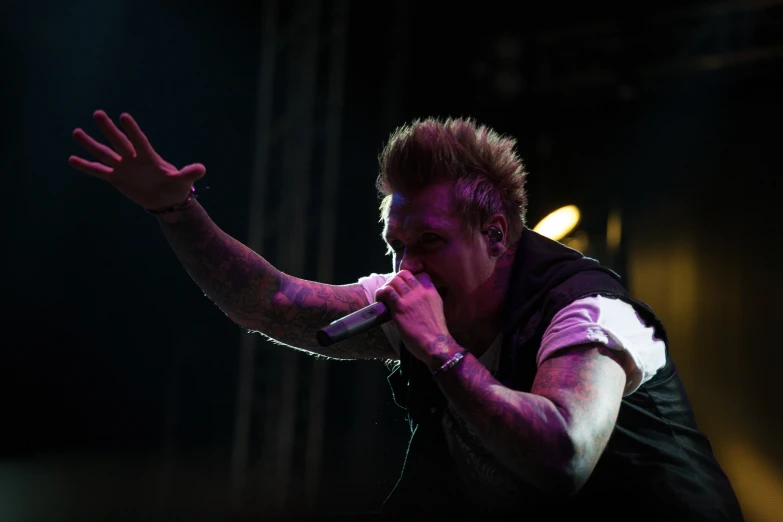 a man with white paint on his face and arm and a microphone in his hand