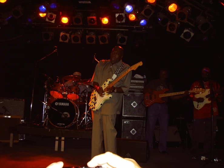 a man playing guitar with other people watching him