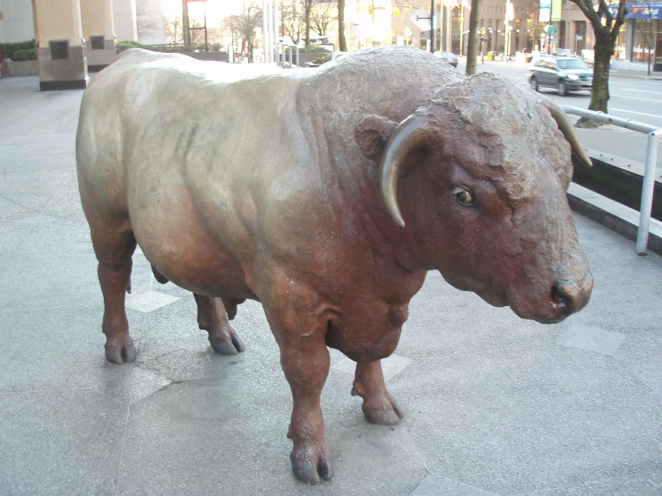 statue of a bull standing on the side of a street