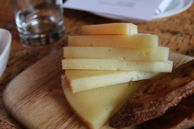 pieces of cheese and a piece of bread sit on a table