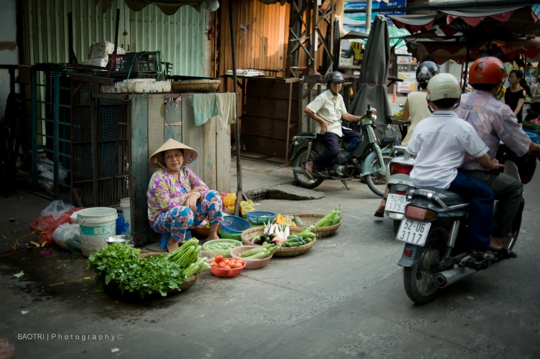 a lady sitting in front of a counter filled with produce