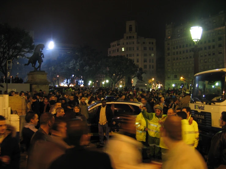 a crowd of people standing near cars at night