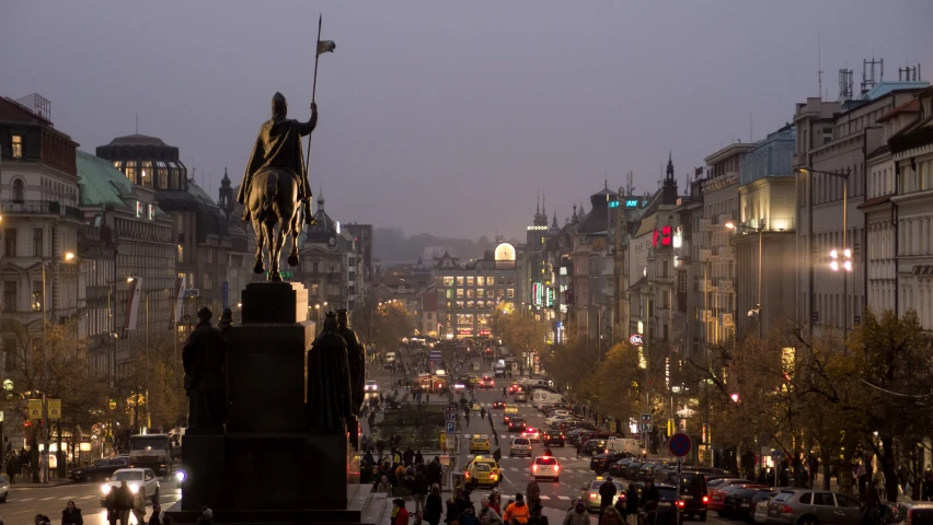 a city street with a statue, some cars and buildings