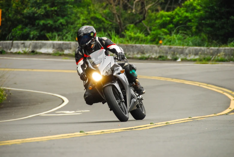 a motorcycle rider with headlights going around a curve