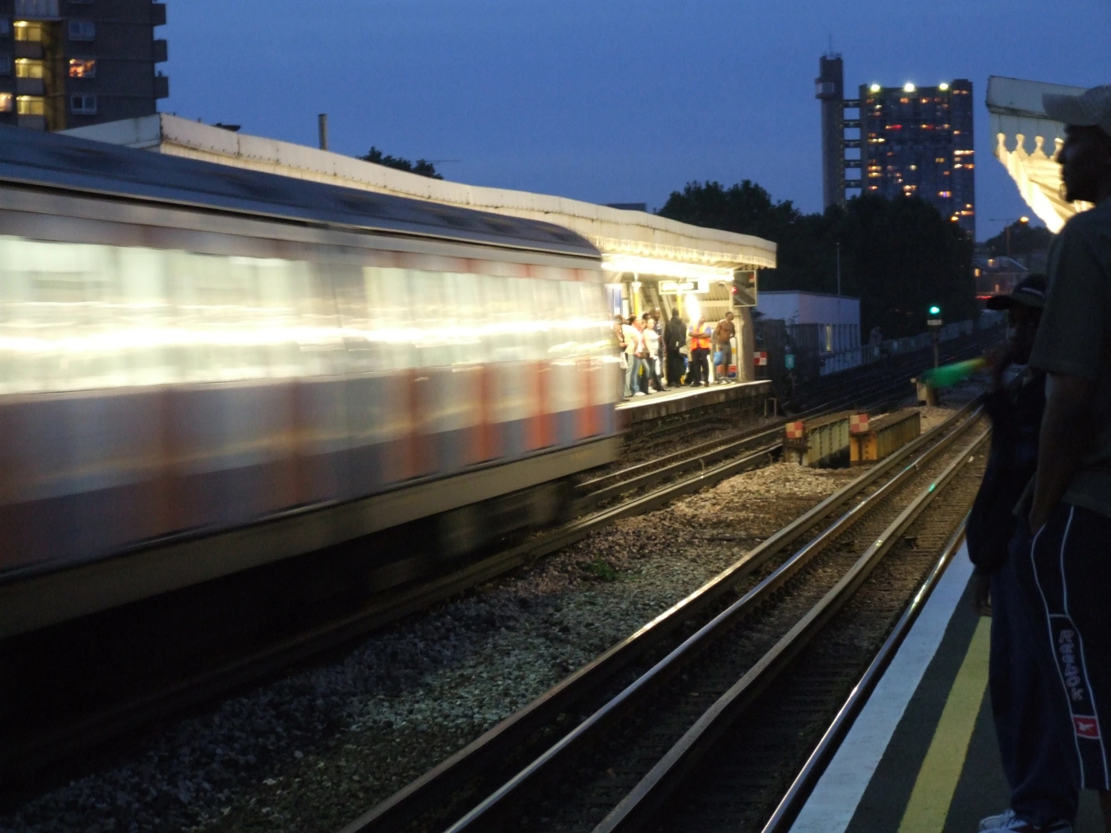 people wait to board the train at night