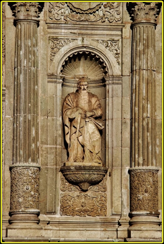 a tall building has an ornate stone fountain and a statue