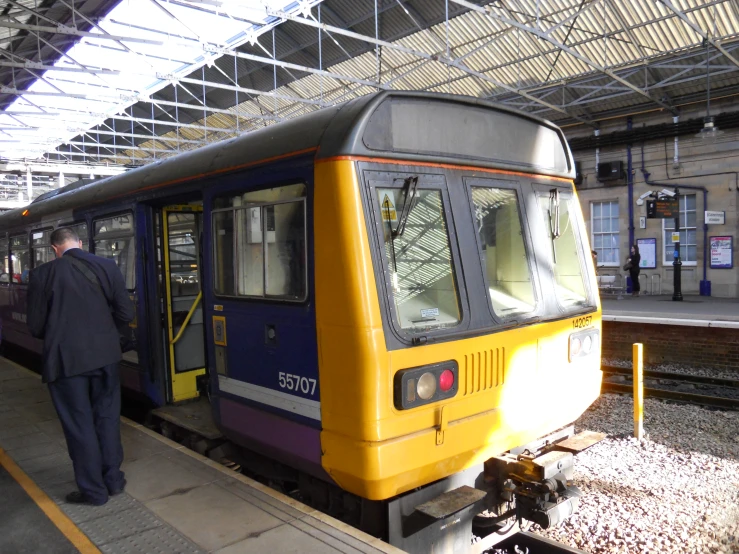 man walking into a yellow and purple train