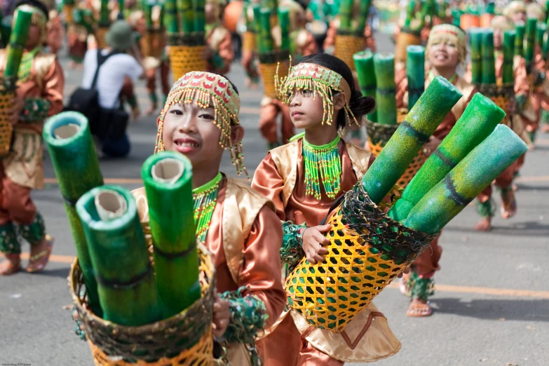 two little children with drums and sticks walking down the street