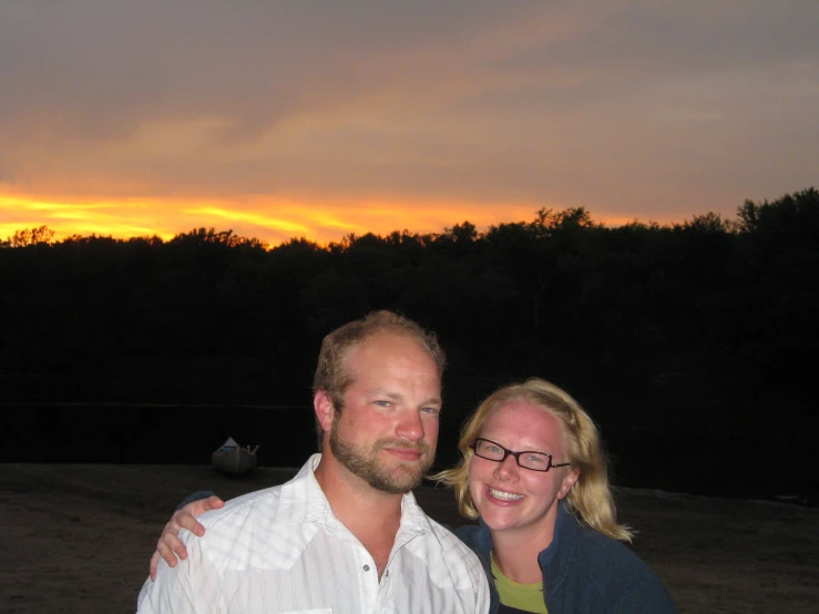 a man and a woman standing together at sunset