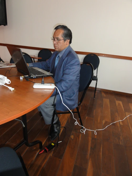 a man sitting in a chair working on his laptop