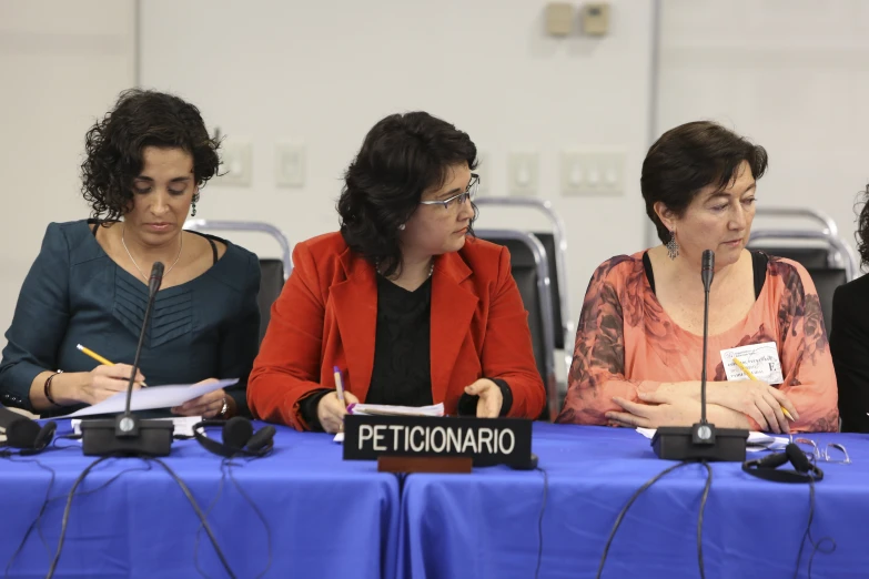 three women sitting behind the table in front of microphones