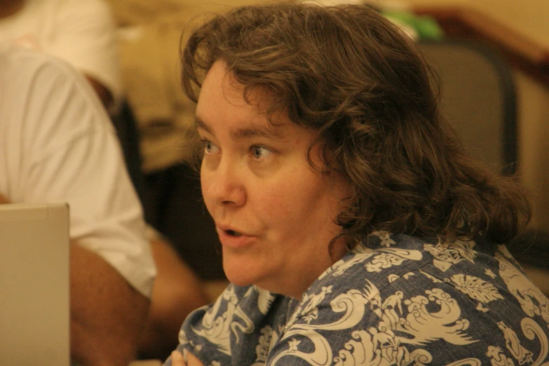 a person with long hair is sitting at a table looking away