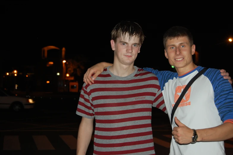 two men in striped shirts posing together at night