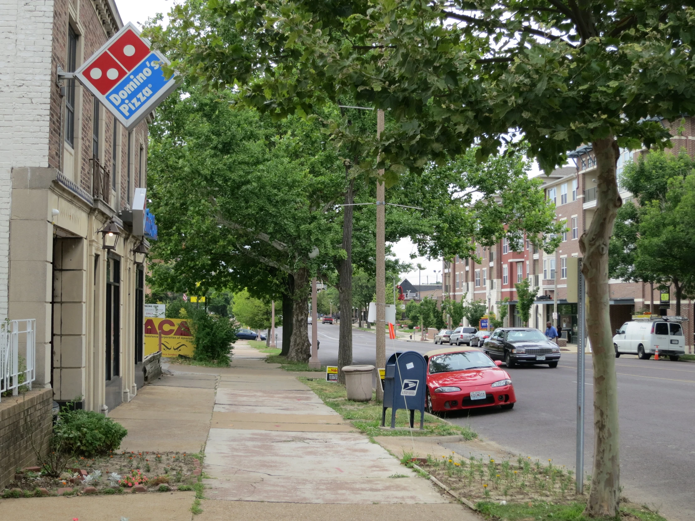 a pizza hut is on a corner street corner with several cars