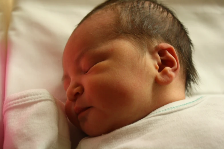 a newborn baby sleeping in a white bed