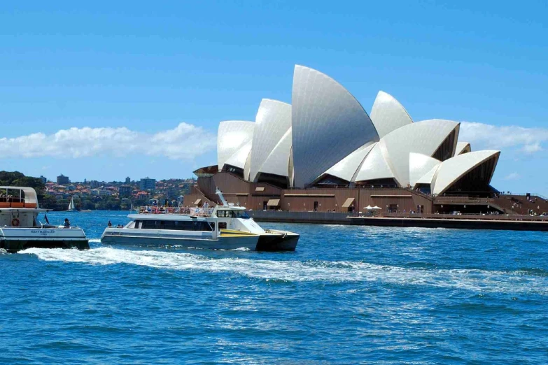 three boats in the water with an opera building in the background