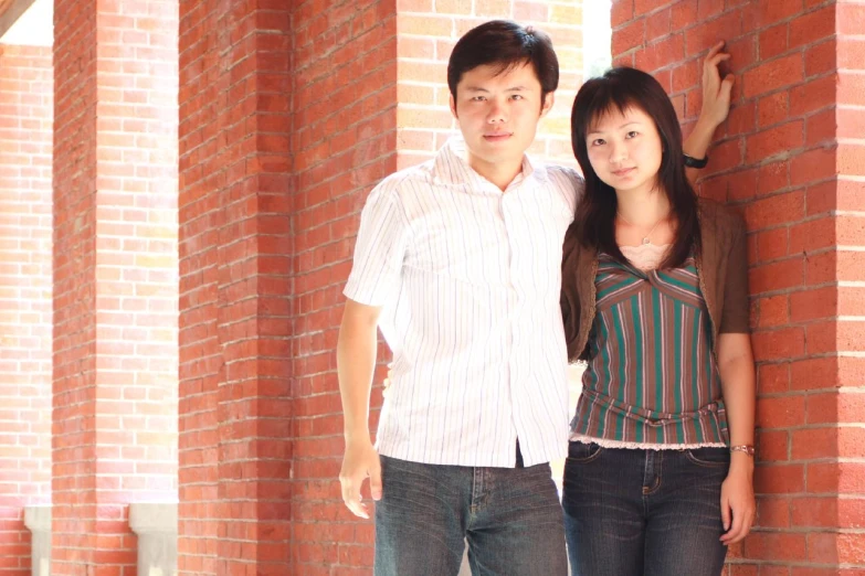 a couple pose on a brick wall together