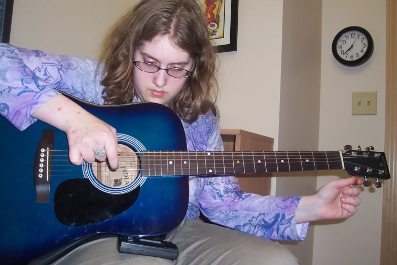  with glasses playing the guitar in the living room