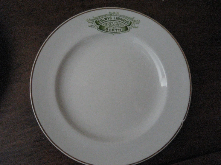 a white dinner plate with green and gold trim